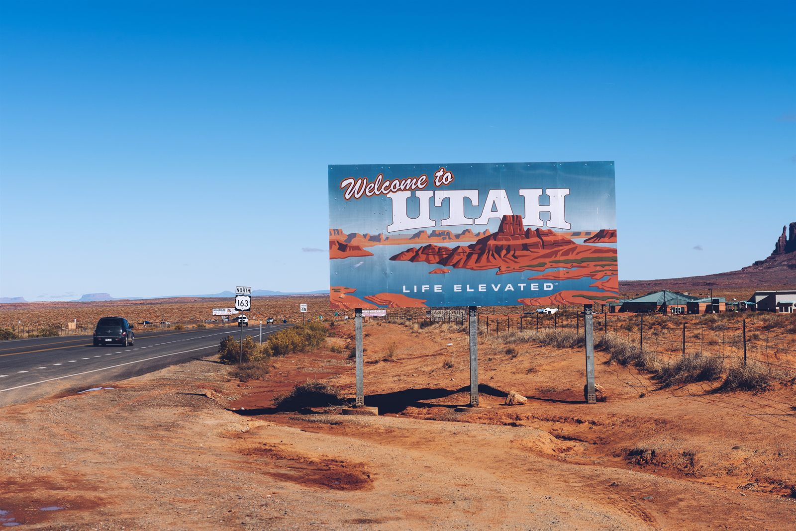 A Welcome to Utah sign beside a desert highway in red rock country, a classic stop on a budget travel USA road trip