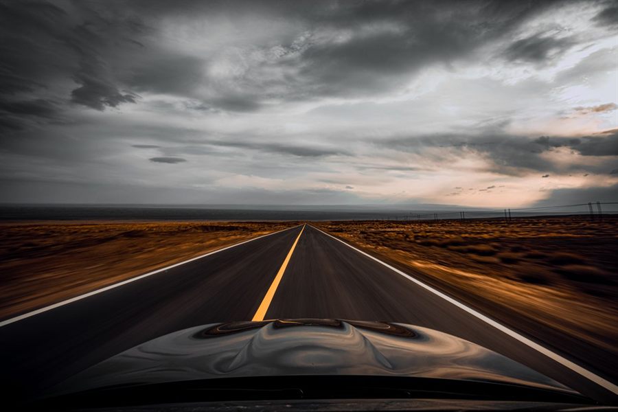 An empty two-lane road under dark clouds