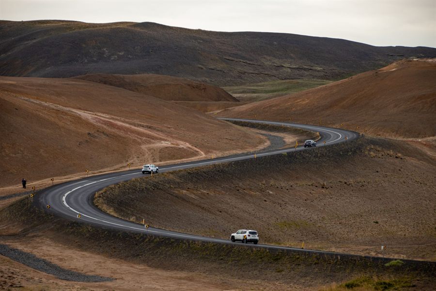 Cars on a road winding through bare brown hills